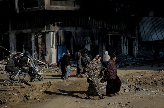 Two women cross the road and are surrounded by destroyed buildings at al-Jalaa Street in the center of Gaza City on 11 January 2024.