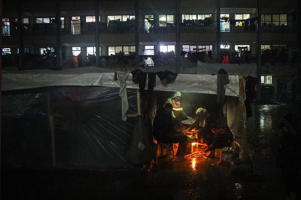 A Palestinian family is seen at a shelter during a rainy night in the city of Rafah, Gaza.
