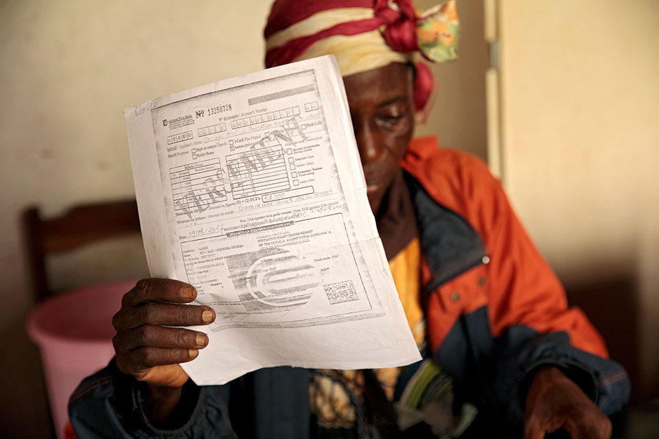 Christine Banlog shows off her oldest granddaughter's exam registration. Photo: UN Women/Ryan Brown