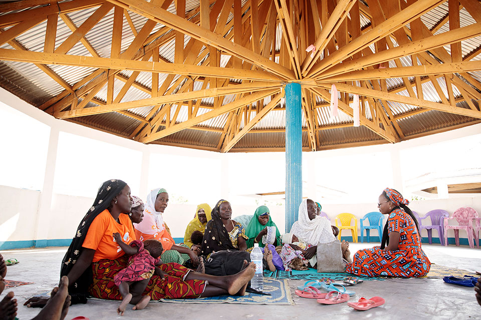 Koche Maina (right) speaks with women at the women’s social cohesion space in the Minawao refugee camp. Photo: UN Women/Ryan Brown