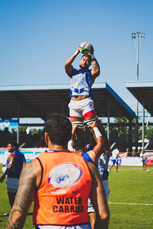 Manu Samoa players warm up for their match against Tonga on 25 June, wearing orange bands to show their support for ending violence against women. UN Women/Ken Tai Tin