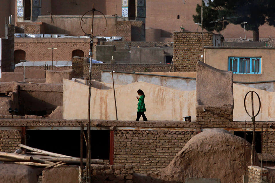 A young girl walks across rooftops against a scenic backdrop, in Herat, Afghanistan. Photo: UN Photo/Eric Kanalstein.