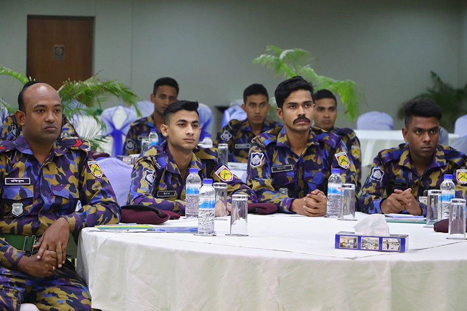 Police officers sit while listening to a training.