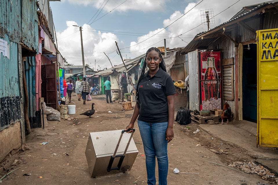 Norah Magero poses for a photo with the Vaccibox, an innovative solar-powered fridge made by her organization Drop Access using locally available materials. Photo: RAEng/GGImages/Alissa Everett.