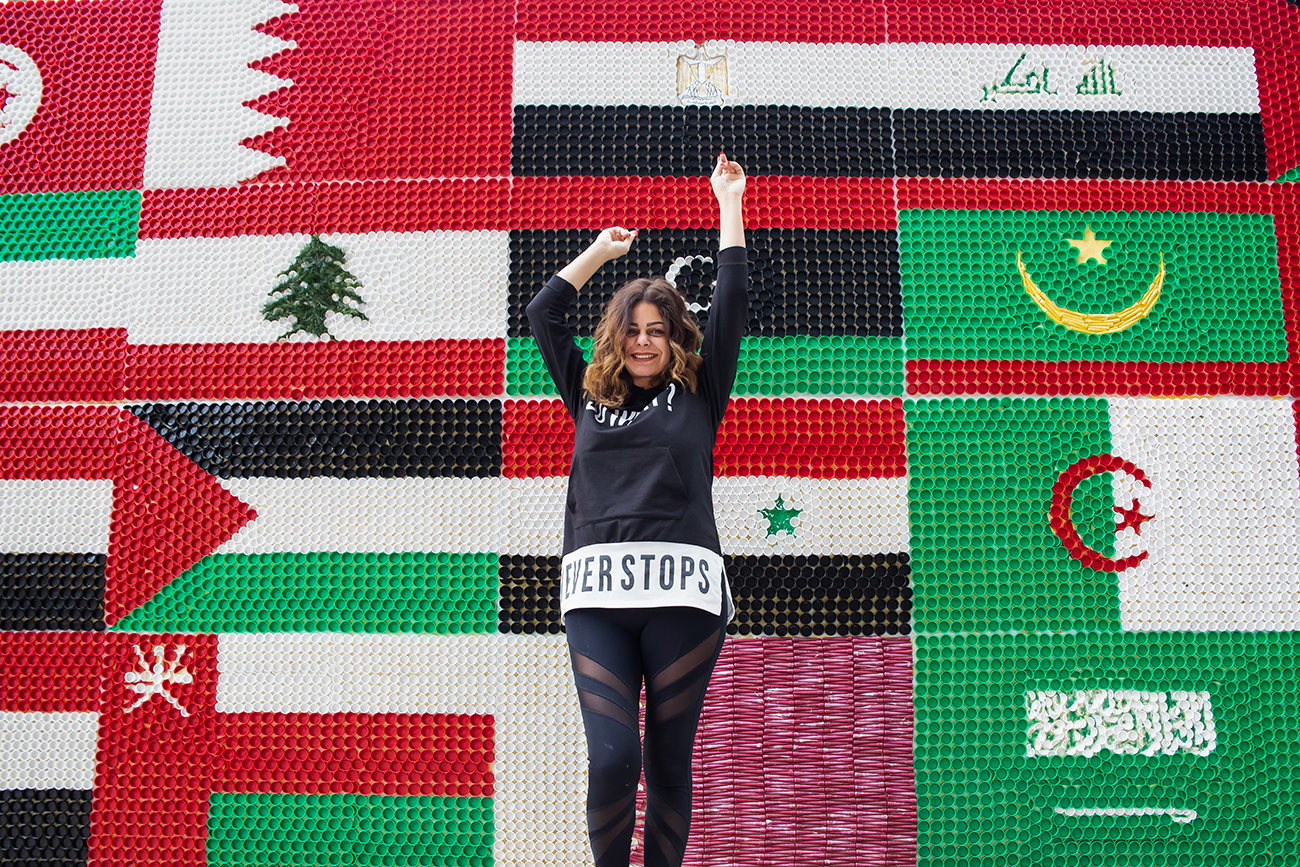 Caroline Chaptini devant une fresque réalisée à partir de capsules de bouteilles dans le bureau de la Commission économique et sociale de l’ONU pour l’Asie occidentale (CESAO) à Beyrouth au Liban. Photo : ONU Femmes/ Lauren Rooney