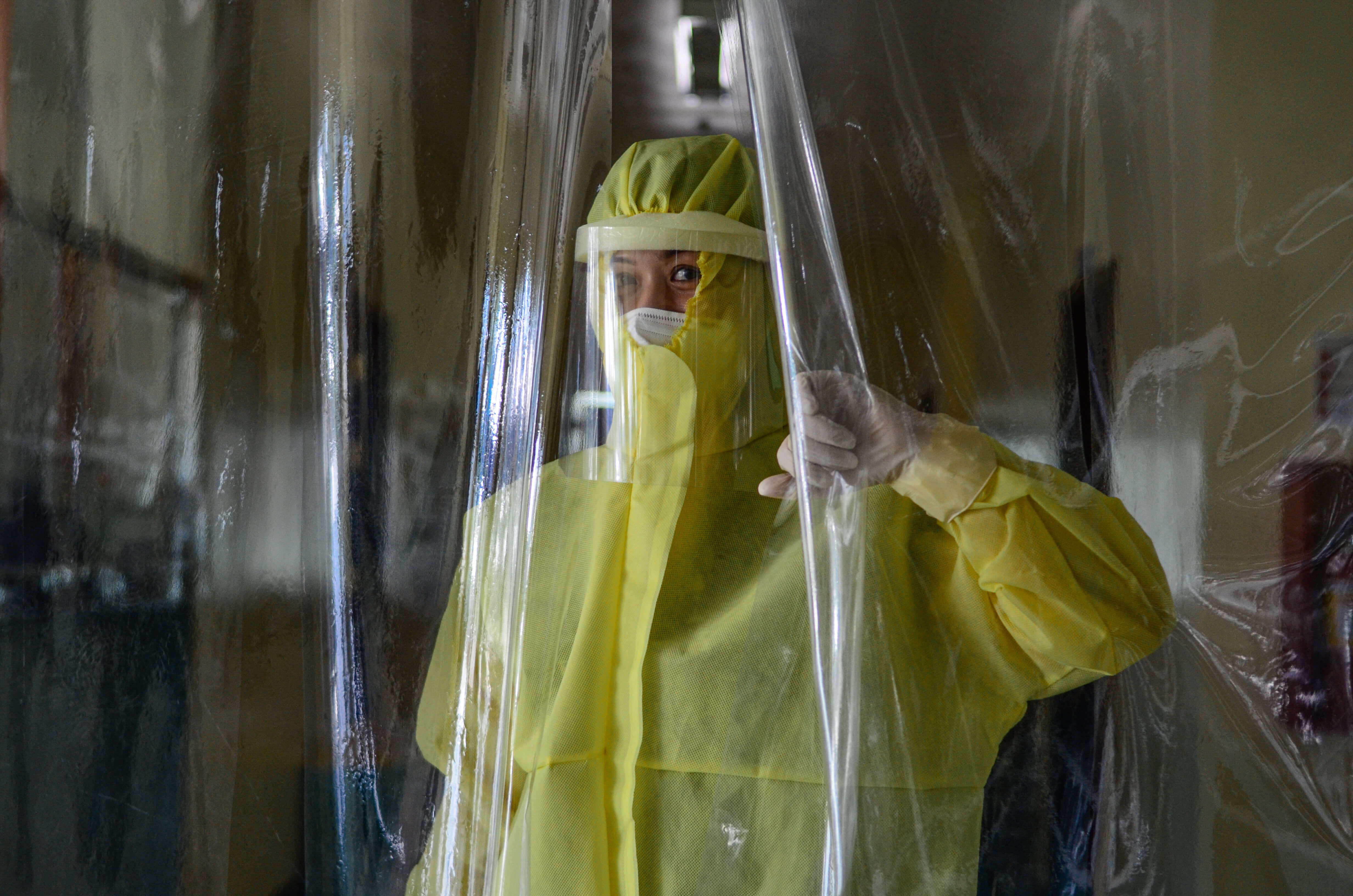 Dre Pamela Solano, obstétricienne-gynécologue et médecin bénévole, regarde par l’entrée de sécurité rudimentaire faite de voiles en matière plastique dans un hôpital de Surralah aux Philippines. Photo : ONU Femmes/Louie Pacardo.