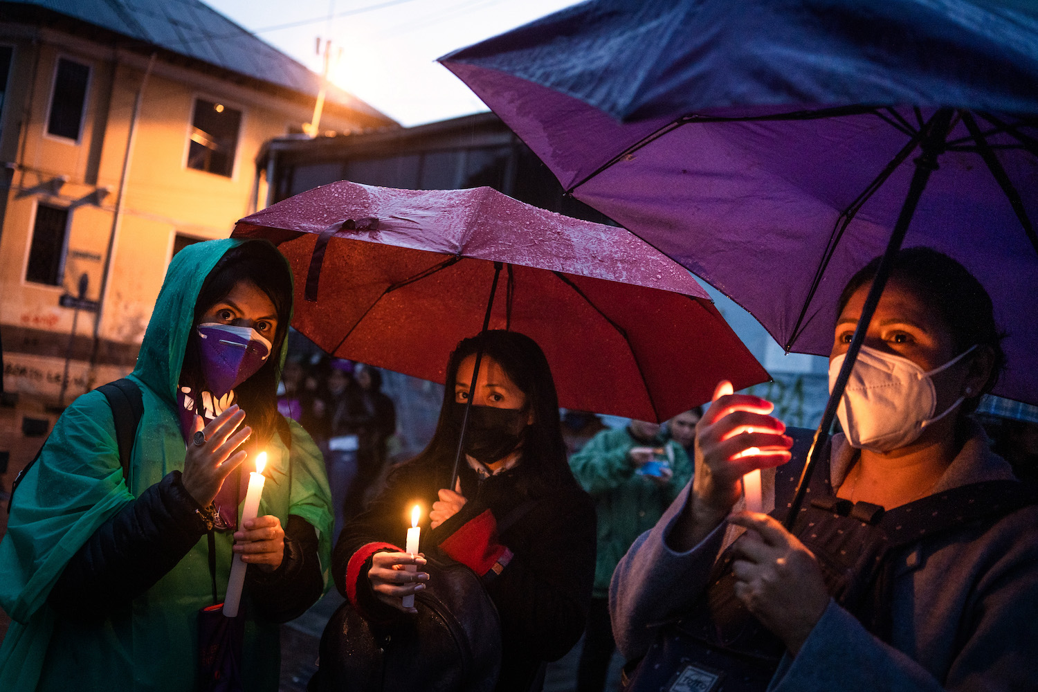 Women attend a candlelight vigil wearing facemasks. 