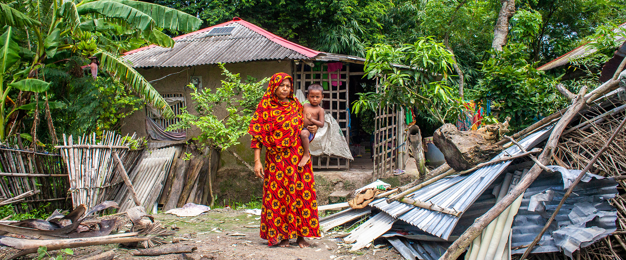 Saleha Begum, 45,  in Patarkhola village of Ramzan Nagar union at Shyamnagar upazila in Satkhira,  stands near some of the remaining damage after the roof of her home was torn off by Cyclone Amphan in 2020.  She received cash support from UN Women following the cyclone, which compounded the hardships already wrought by the COVID-19 pandemic. Photo: UN Women/Fahad Kaizer
