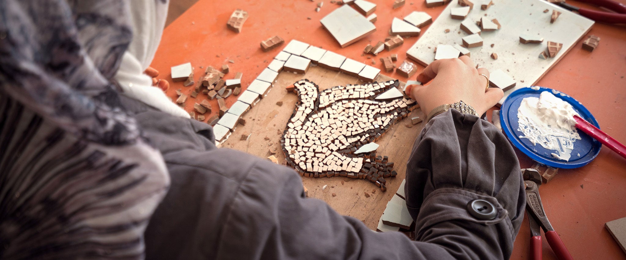 Camp de réfugiés Za’atari, en Jordanie, 2015. Une femme travaille à une mosaïque représentant une colombe, symbole de paix. ONU Femmes propose des programmes d’autonomisation économique et de protection aux femmes et aux filles vivant dans ce camp. Photo : ONU Femmes/Christopher Herwig