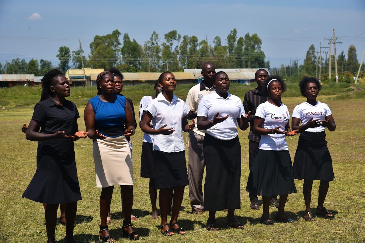 Une chorale locale se produit lors d’un dialogue communautaire ou « baraza » dans le comté de Kisumu, au Kenya. Les groupes ethniques de Kisumu et du comté voisin de Nandi ont connu une tension accrue à l’approche des élections générales dans le pays. Photo : ONU Femmes/Luke Horswell 