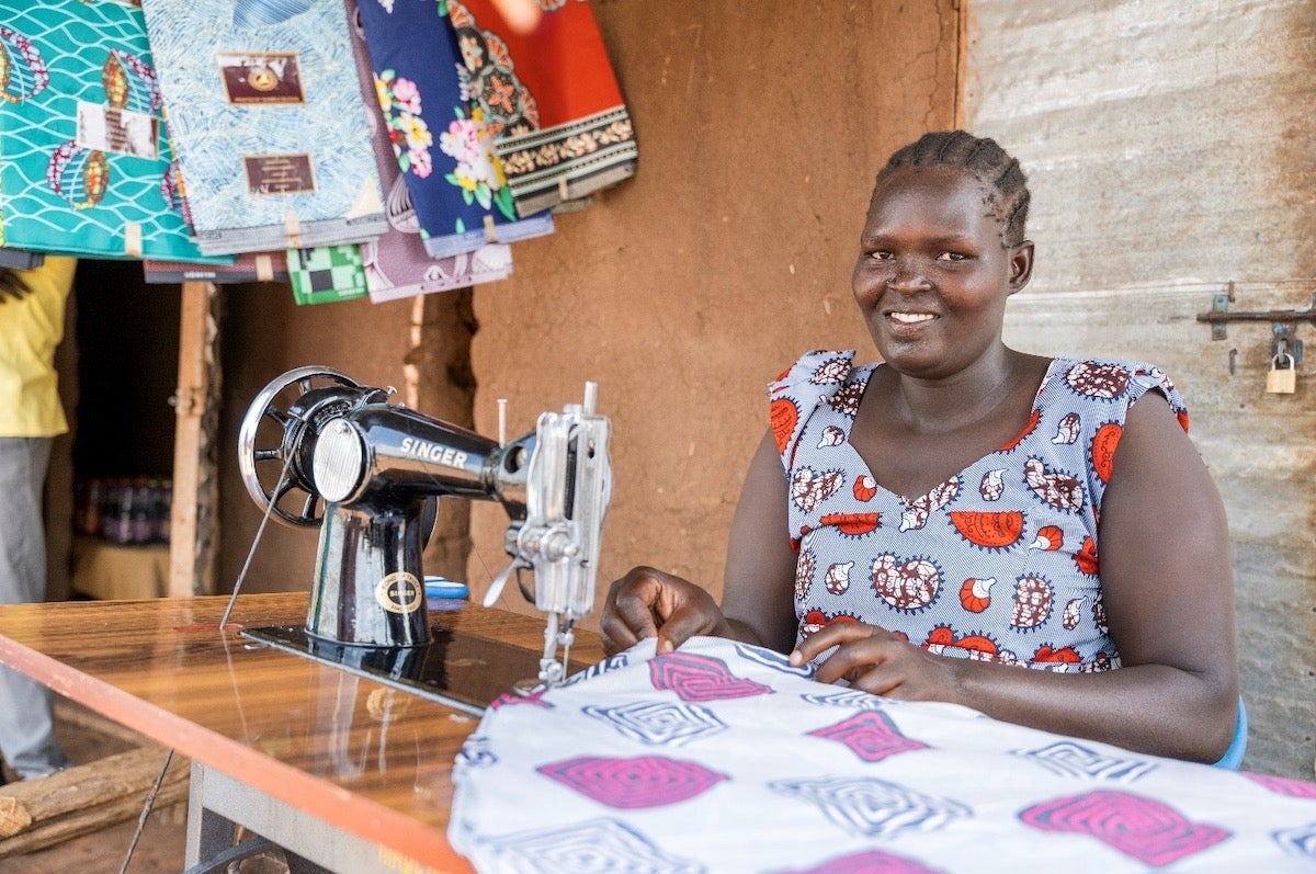 Alice Ledu in Bidi Bidi Settlement attending to the tailoring enterprise that she started using proceeds from her catering business skills. Photo: UN Women/Jeroen van Loon