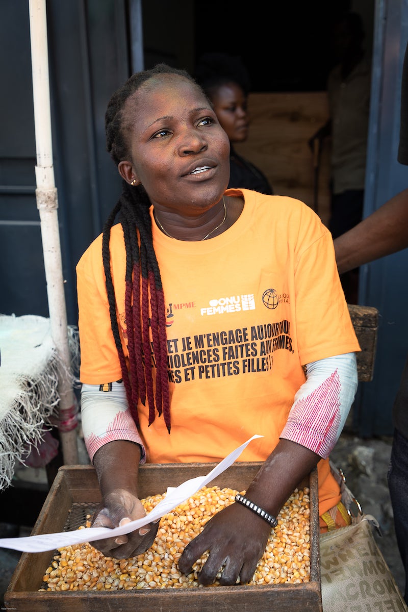 Malala Nzola, 38, a cassava and corn flour seller, holds her official business registration document. Photo: UN Women/Yulia Panevina