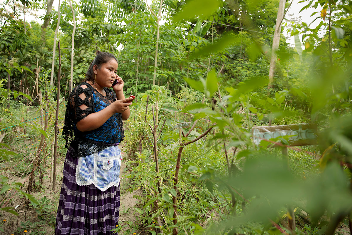 Elena Sam Pec, que aparece en la foto atendiendo una llamada de teléfono mientras lee un mensaje en otro, vive en Puente Viejo, Guatemala, en una comunidad indígena fundamentalmente agrícola que depende de las canoas de madera para transportar mercancías y acceder a los servicios.