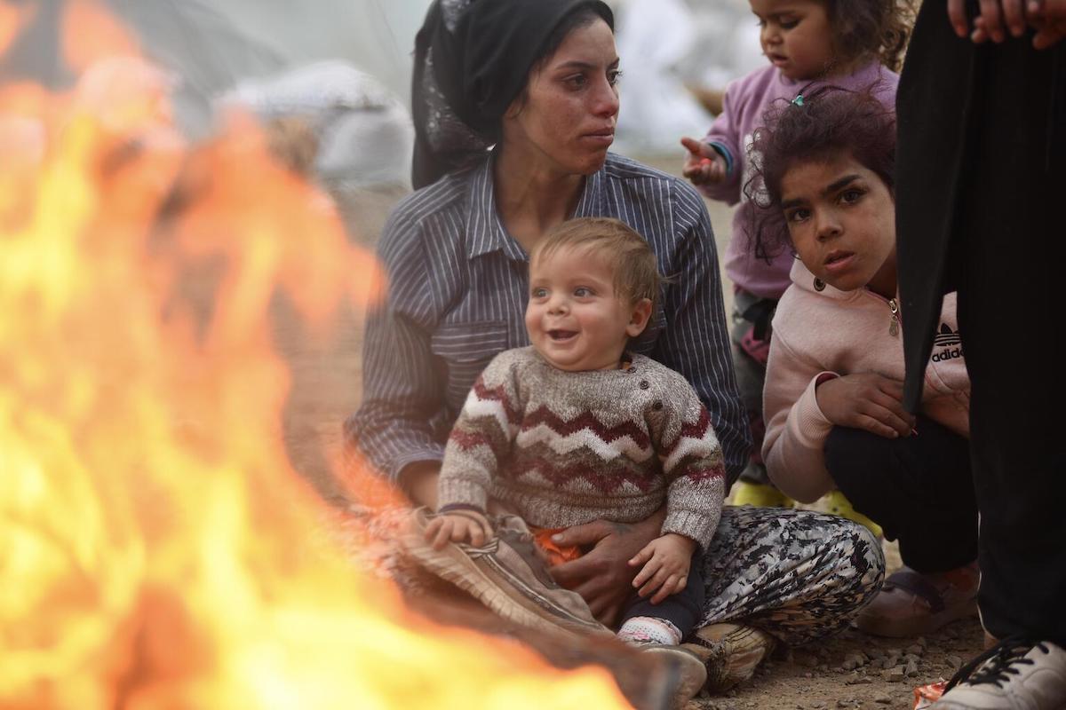 Survivors of the 7.7 magnitude earthquake keep warm by a fire in a temporary shelter in Kahramanmaraş, Turkey. The affected region of south-east Turkey and Syria was already severely disrupted by the nearly 12-year conflict in Syria, and ethnic tensions in Turkey. Photo: UNICEF/Ölçer