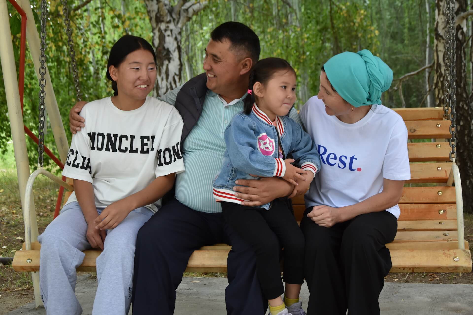  Gulnaz Almambet kyzy and Rakhat Asankul uulu sit on a bench with their two daughters. Photo: Education Community Development