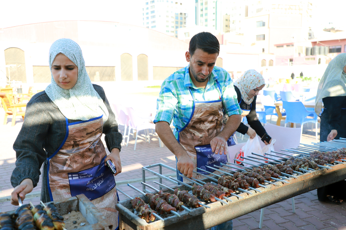 Muhammad Kaddass cooks alongside women in Palestine. Photo: Aisha association for women and child protection
