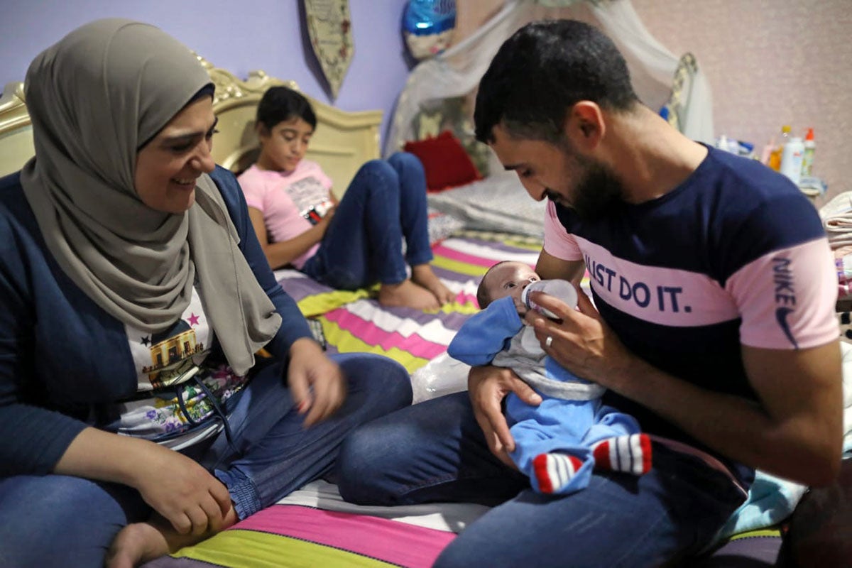 A man is seeing feeding a baby in Tyre, Lebanon, in 2020. 