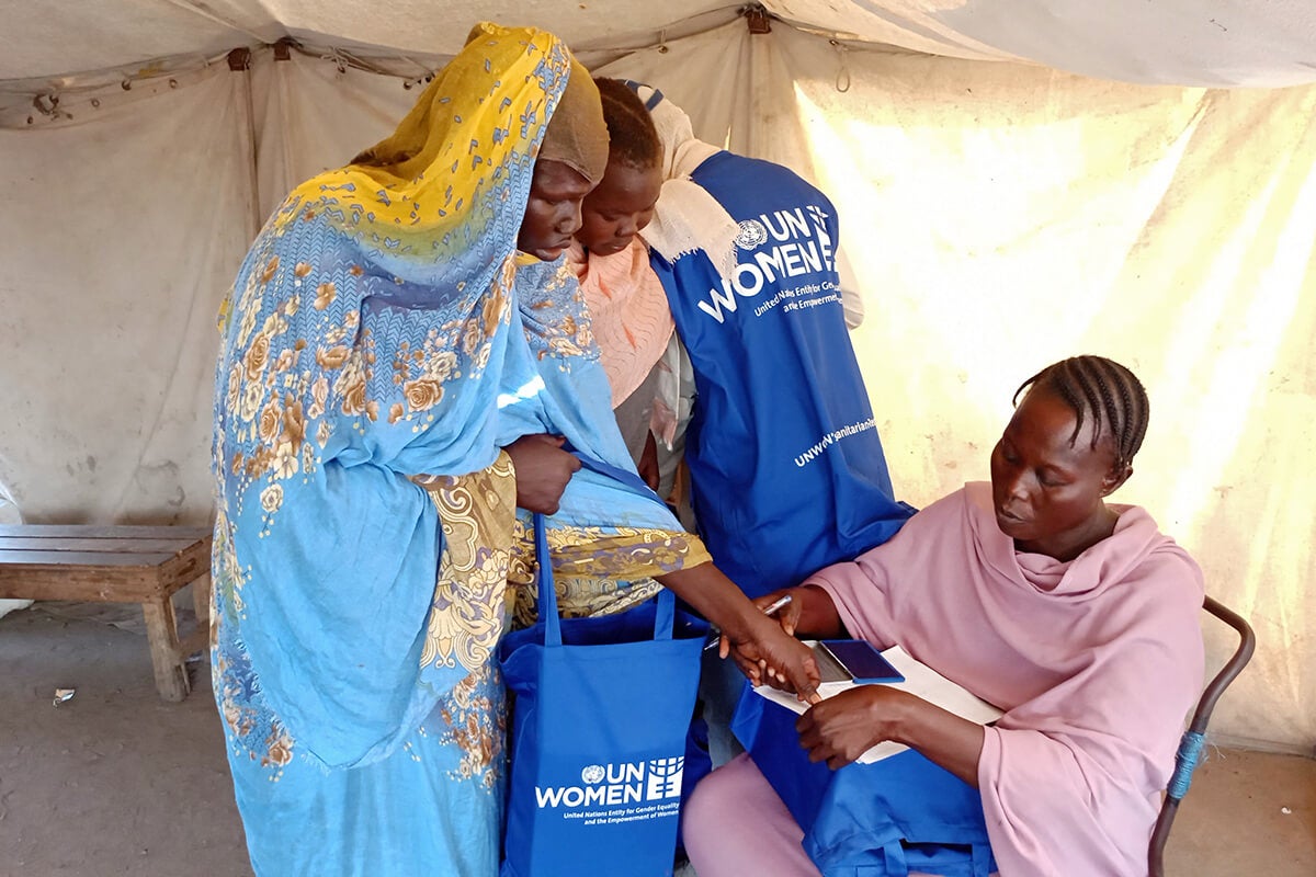Internally displaced women are seen receiving hygiene kits from a volunteer at a shelter in Port Sudan.