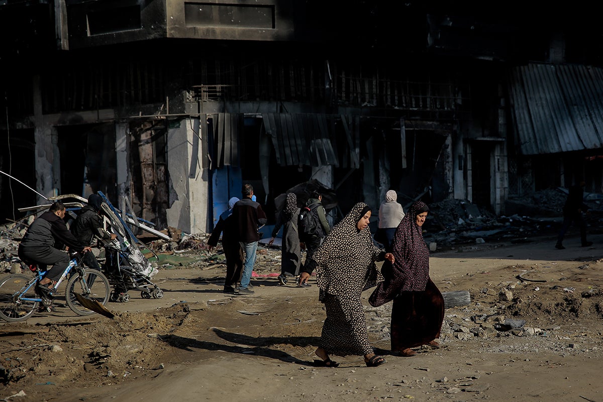 Two women cross the road and are surrounded by destroyed buildings at al-Jalaa Street in the center of Gaza City on 11 January 2024.