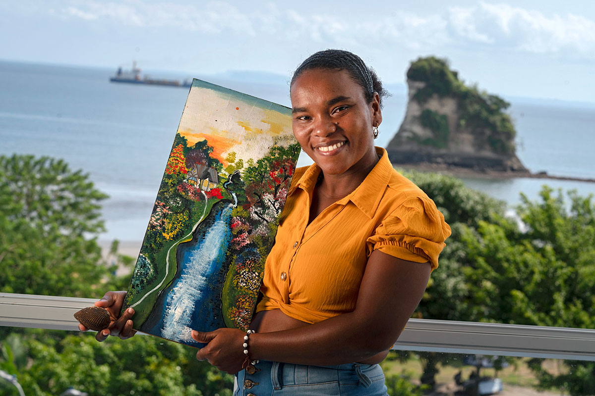 Anabel Magallanes displays a piangua, the shelled mollusk she harvests artisinally in Tumaco, and a painting representing the estuaries full of mangroves where they are harvested.