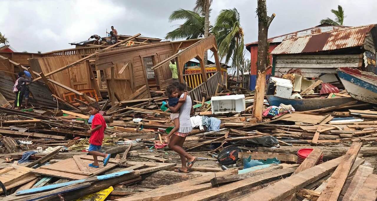 A mother and her children walk through ruined housing in the wake of Hurricane Iota in Puerto Cabezas, Nicaragua. Photo: UNICEF/Inti Ocon/AFP-Services.