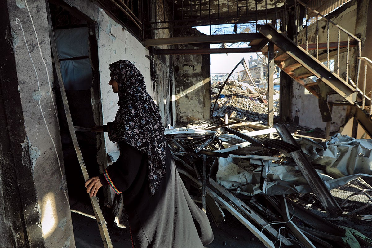A woman in Gaza looks through the rubble of her devastated home in February 2025. Photo: UN Women/Suad Al Nawajha