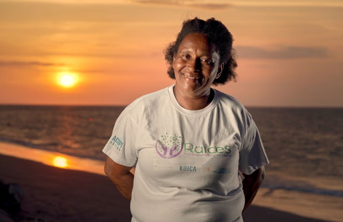 A smiling woman wearing a t-shirt from the Raíces del Manglar Association