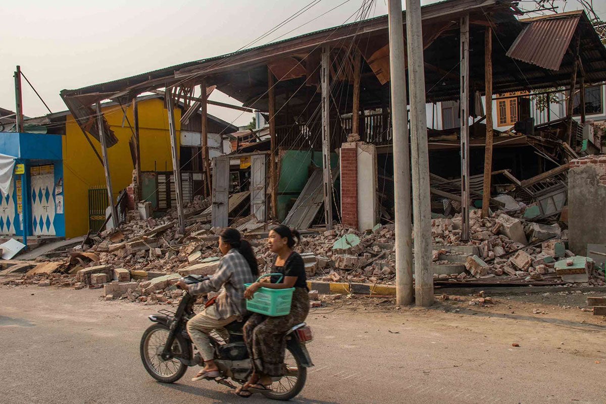 On 31 March 2025, two women are seen riding a motorcycle, passing by a collapsed building in Sagaing, Myanmar, following the 7.7-magnitude earthquake that struck Mandalay on 28 March. Photo: UNICEF/UNI771892/Htet