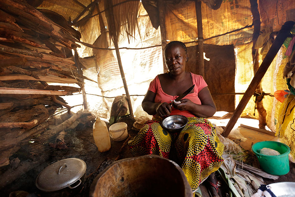 A woman cooks using cassava and wraps them in large forest leaves to sell at the Gado-Badzere market. Photo: UN Women/Ryan Brown