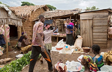 Hawa sells bags of cassava flour, dried fish and nuts at the camp’s marketplace. Photo: UN Women/Ryan Brown