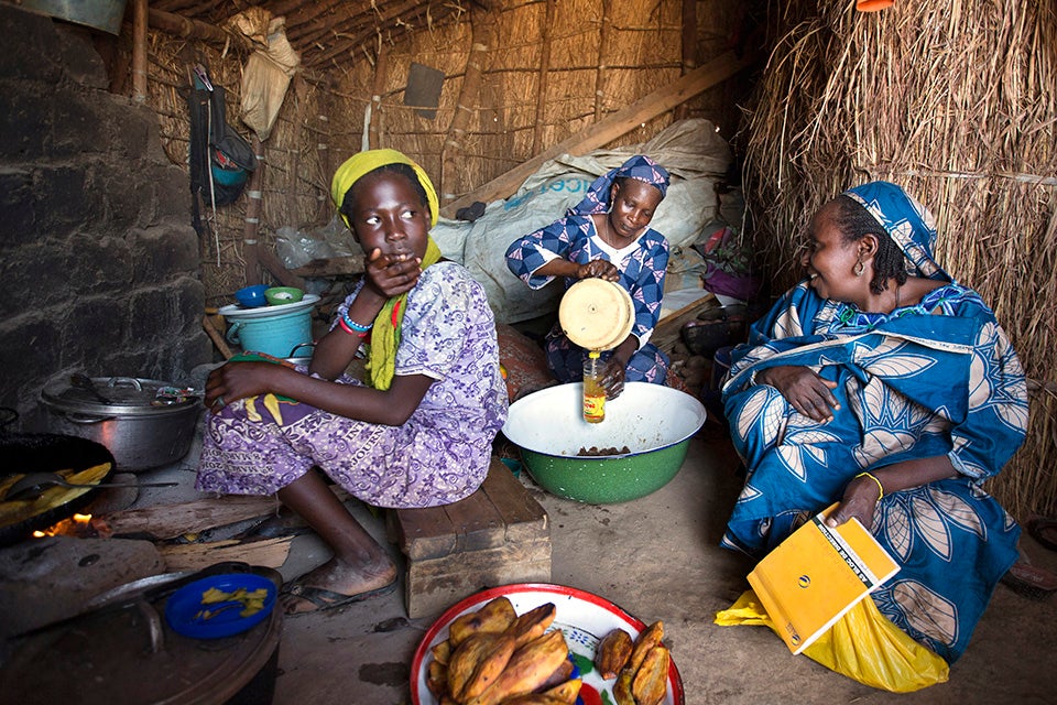 Nene (centre) and one of her daughters, Salamatou Abubakar (left), 12, have been providing food to many refugees at a makeshift restaurant in a small market at the camp. Photo: UN Women/Ryan Brown