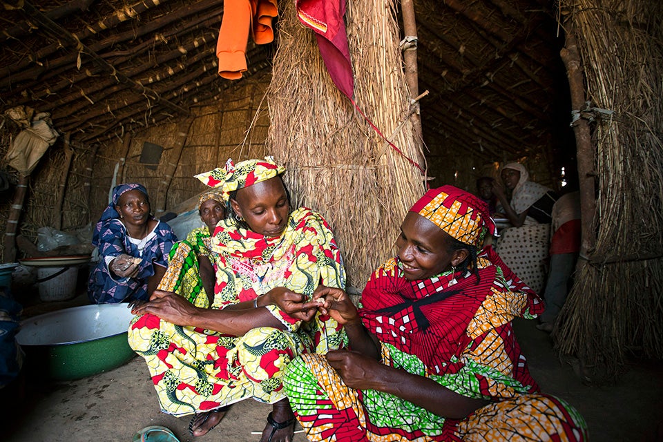 Nene passes out bites of dough to tide visitors over while she finishes cooking. Photo: UN Women/Ryan Brown
