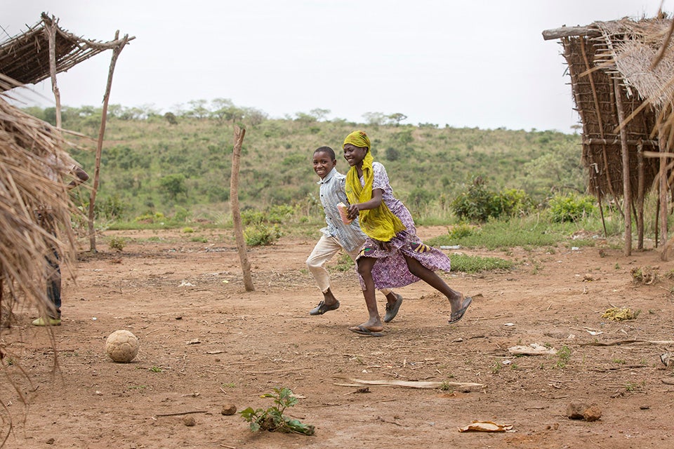 Salamatou, steps outside to cut herself slices of mango as a snack. She sees a group of boys nearby playing football and immediately runs to join them, forgetting, at first, to put down her mango-slicing knife. Photo: UN Women/Ryan Brown