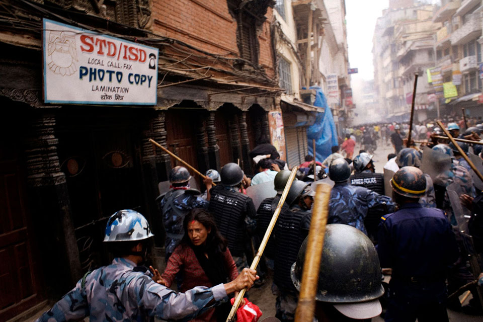 NEPAL. Kathmandu. 2006. During political protests in Nepal in 2006, people took to the streets, pushed through into the central old part of Kathmandu, and, at Ason Chowk, they were confronted by police. After 10 years of armed conflict in Nepal, the transition continues to provide many opportunities for women to engage in peacebuilding. UN Security Council resolution 1325 and its subsequent six resolutions recognize the participation of women in peacebuilding processes as key to sustainable peace, economic recovery, social cohesion and political legitimacy.  ©Jonas Bendiksen/Magnum Photos