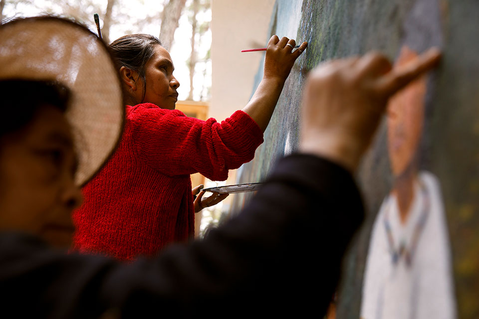 Artists María Nicolasa Chex and Paula Nicho Cumez paint scenes of indigenous cultural life on one of the murals adorning the “Center for the Historical Memory of Women” outside of Comapala. Photo: UN Women/Ryan Brown
