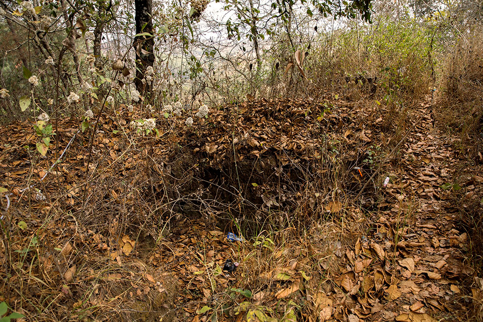 Leaves and debris surround one of the three open pits on the memorial grounds. Three sites were left uncovered after exhumations took place and are intended to grow over naturally in order to be seen and remembered. Photo: UN Women/Ryan Brown