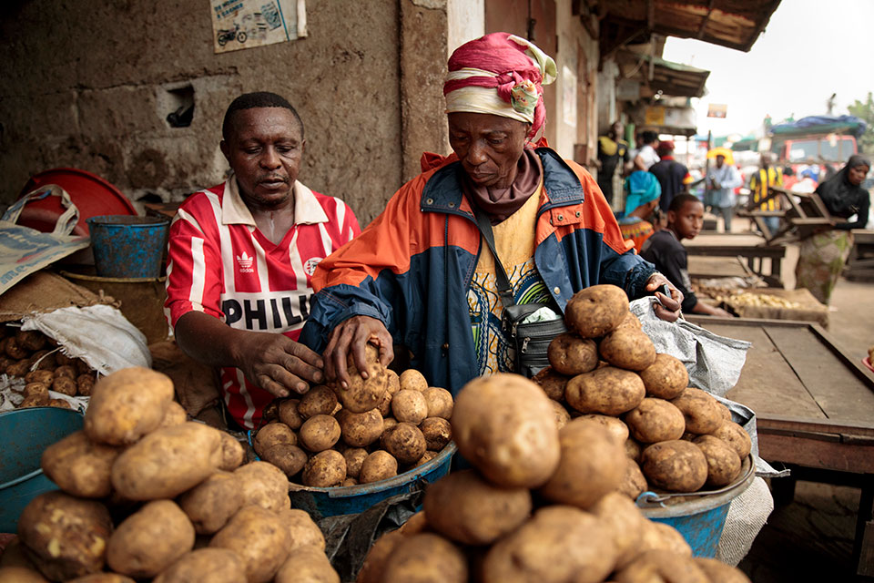 Christine Banlog chooses potatoes from a whole-sale market. Photo: UN Women/Ryan Brown