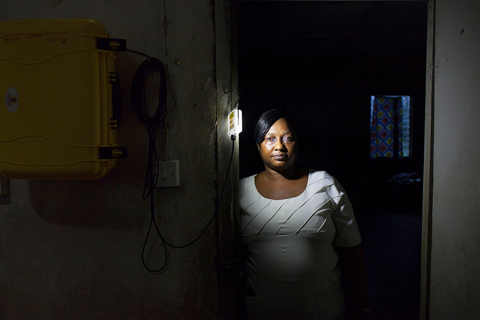 Midwife Zainab Manserray from Masougbo Chiefdom Primary Health Unit in Bombali District, Sierra Leone, poses with a solar lighting system funded by UNFPA as part of the H6 Partnership. H6 Partnership/Abbie Trayler-Smith
