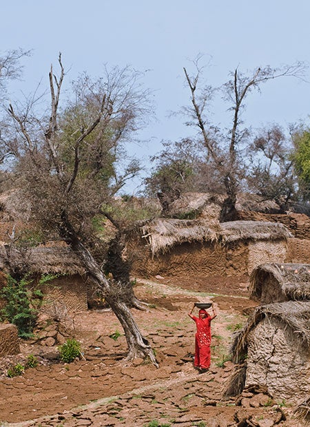 A woman in rural India travels along a footpath, carrying sweets on her head to sell in a local market. UNDP/Amitava Chandra