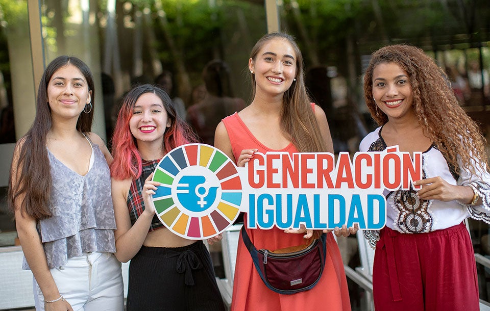 Young women in Mexico hold up Generation Equality signs.