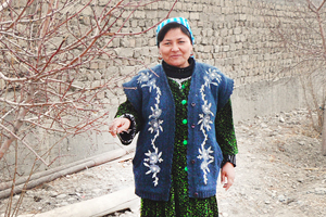 Anjira Ashurova se tient dans le jardin de sa maison. Crédit photo : Association des Femmes et de la Société