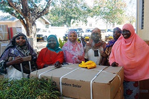 Proudly displaying their consignment of solar equipment, the six Tanzanian solar engineers (from left to right) are: Esha Mohamed Mwanga, Sofia Hamisi Mnandi, Amina Hassani Nachingulu, Fatima Mohamed Mzungu, Mariam Issa Luwongo and Arafa Mwamba Halfani. Photo credit: Lesley Reader