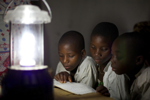 Enfants faisant leurs devoirs en fin de journée grâce aux lampes solaires du village de Chekeleni, près de Mtwara, en Tanzanie. Crédit Photo : VSO/Ben Langdon.