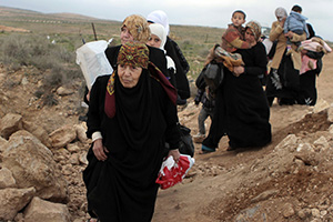 A line of Syrian refugee women, some carrying children, cross into Jordan from southern Syria in February 2013. Photo credit: UNHCR/N. Douad