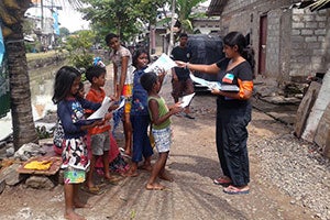 Chamathya (right) distributes lealfets for children in a low-income urban settlement in Colombo. Photo: Kavishna Thangarajh