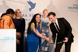 Jefa interina de ONU Mujeres Lakshmi Puri y el moderador Ingo Nommsen sostienen el Premio de Cinema for Peace para ONU Mujeres durante una cena de honor en Soho House el 12 de julio de 2013 en Berlín.