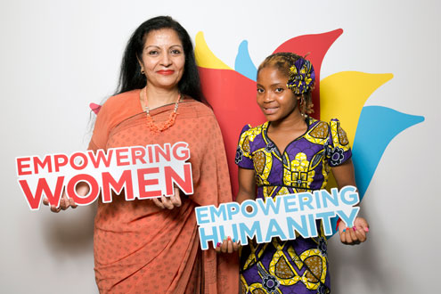 Ms. Puri and Raquelina pose in front with the logo for UN Women's Beijing+20 campaign. Photo: UN Women/Ryan Brown