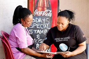 Ayda Ramatsiba Maphefo (left), woman entrepreneur and Portia Tsienyane (right), Hand-In-Hand Trainer discuss Maphefo's financial books during a follow up meeting. Photo: UN Women South Africa