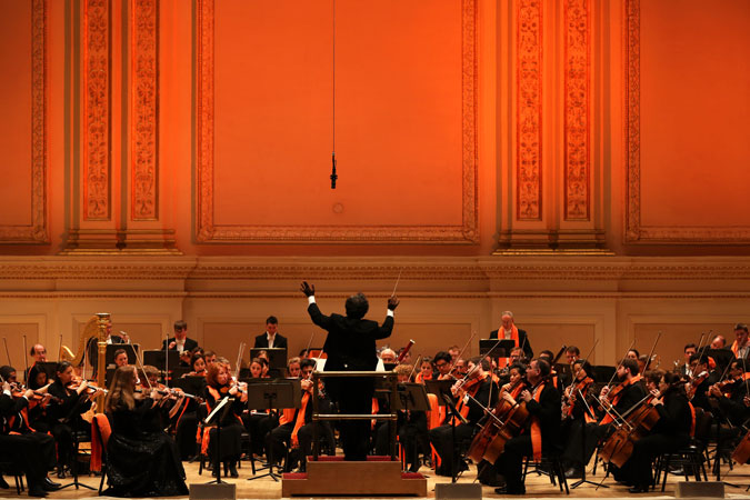 Musicians pack a powerful performance in Carnegie Hall, against the orange-lit backdrop of the concert hall stage. Photo: UN Women/Ryan Brown