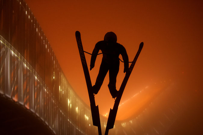 In Oslo, Norway the statue of a skier stands out against the orange-lit backdrop of the Holmenkollen ski jump. Photo: Susanne A. Finnes